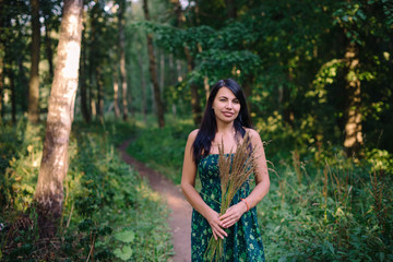 Beautiful woman standing in the woods with a bouquet of spikelets