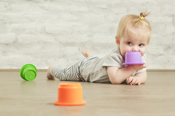 Baby girl playing on the floor with plastic educational   cups, early learning concept