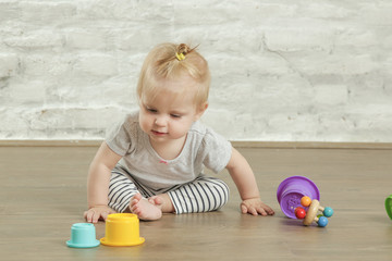 Baby girl playing on the floor with plastic educational   cups, early learning concept