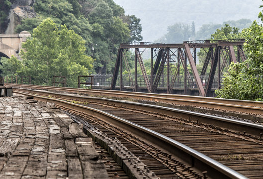 Two sets of train tracks parallel each other over a river and into a tunnel