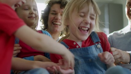 Medium shot of happy family with three children having fun together on sofa, cuddling and laughing