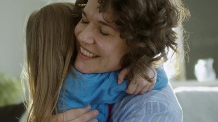 Close up face of loving mother smiling when embracing affectionate little daughter of primary school age