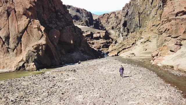 Aerial over a woman walking into a deep and mysterious canyon in Askja, central highlands of Iceland.