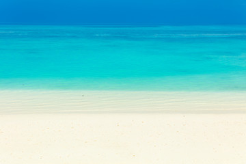 Fototapeta na wymiar Blue sea water surface, clear sky and sandy seashore