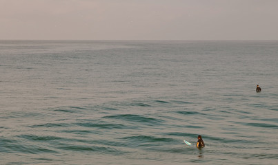 Two surfers in the Pacific ocean sitting on their surf boards waiting for a wave in southern California, USA