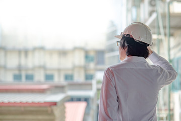 Asian male engineer or architect wearing protective safety helmet at construction site. Engineering, Architecture and building construction concepts