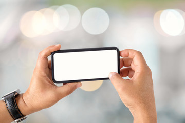 Unrecognizable man showing a blank screen mobile phone over blurred bokeh background