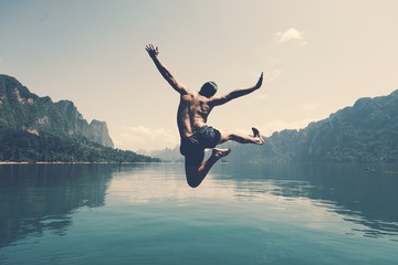Fototapeta Man jumping with joy by a lake obraz
