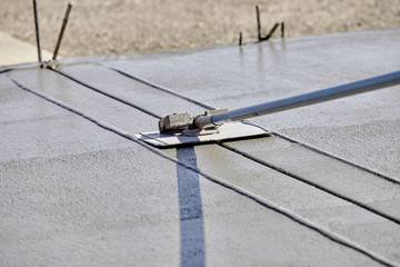 A mason using a concrete groover to finish a concrete slab
