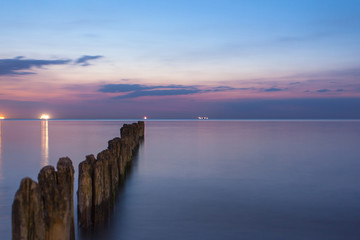 smooth sea surface and breakwaters in purple twilight on long exposure