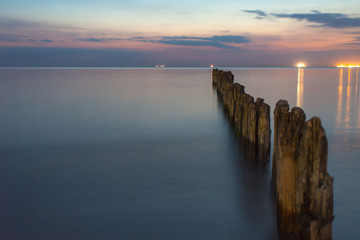 smooth sea surface and breakwaters in twilight on long exposure