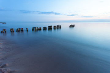 smooth sea surface and breakwaters in blue twilight on long exposure
