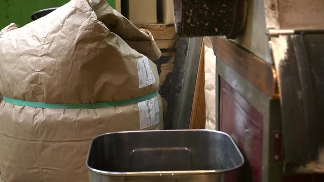 freshly dried tea pours into a container at nishiki market in kyoto, japan