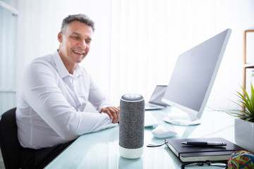 Man Listening To Wireless Speaker In Office