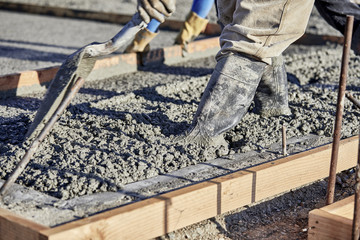 Mason spreading wet Cement with a shovel