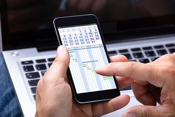 Man Analyzing Gantt Chart On Cellphone