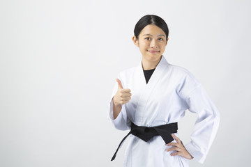 空手着を着て指を立てる若い女性