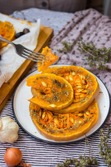 Woman hands takes backed sweet orange pumpkin round slices with oregano, garlic, olives and spices. Vegan lunch, vegetarian dinner, healthy food, vegetables. Delicious organic diet