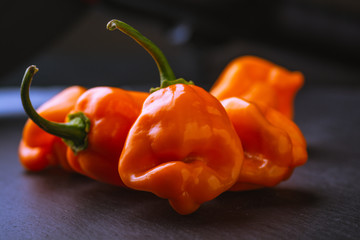 Grouping of raw orange habaneros on a slate surface