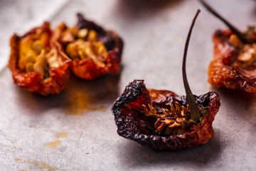 Grouping of oven roasted habaneros on a baking tray that have been cut open.