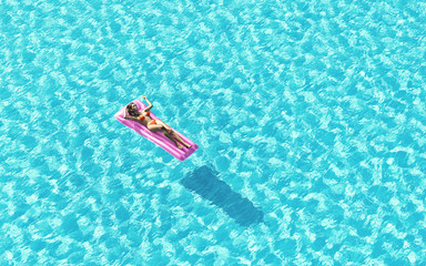 Woman relaxing on water mattress in the pool.