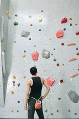 Young man looking at bouldering wall before climbing © DragonImages