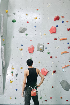 Young man looking at bouldering wall before climbing