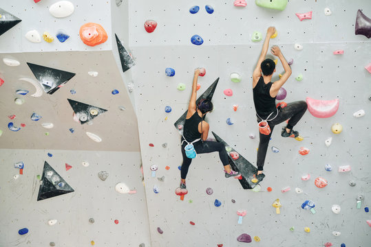 Couple enjoying climbing on artificial wall in gym