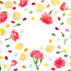 Roses flowers and petals with bright sugar candy on white background. Flat lay, top view.