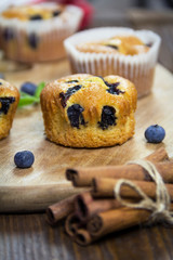 Muffins with blueberries, chocolate and cinnamon on a wooden board. Sweet dessert