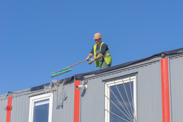 Worker at the construction site cleans the roof of the water with a brush