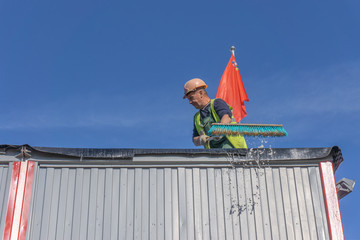 Worker at the construction site cleans the roof of the water with a brush