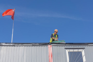 Worker at the construction site cleans the roof of the water with a brush