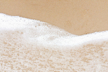 Closeup on bubble soft wave of the ocean wave on sandy beach background in summer tropical season.