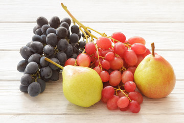 Fresh colorful grapes red and blue with sweet pears on white wooden table