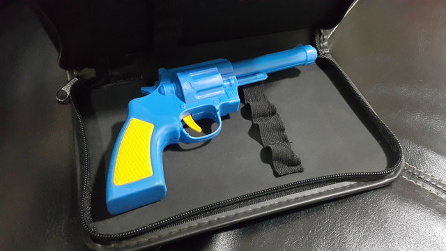 Blue plastic gun A yellow handle and trigger is placed in the black leather case.