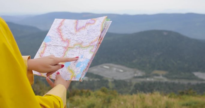 Young female Hiker looking at map from mountain top
