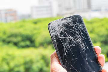 Smartphone drop to the floor and screen damage broken in hand with green bokeh