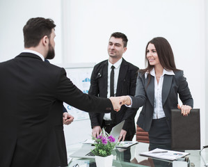  handshake business partners at the meeting near the desktop in a modern office