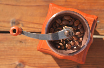 Handmade coffee grinder with coffee beans on wooden planks