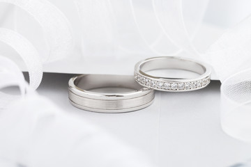 Two silver wedding rings with diamonds on gray background