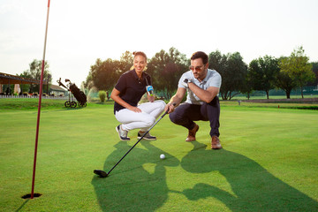 Obraz premium Young sportive couple playing golf on a golf course