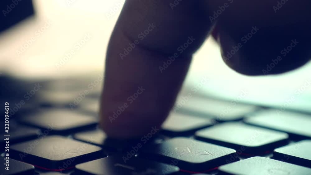 Poster Man typing keyboard on laptop computer. backlit with shallow depth of field. Closeup
