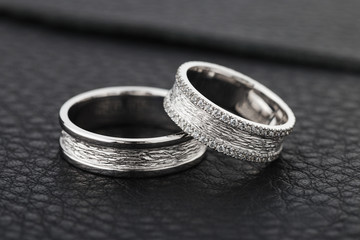 Two silver wedding rings on black leather background