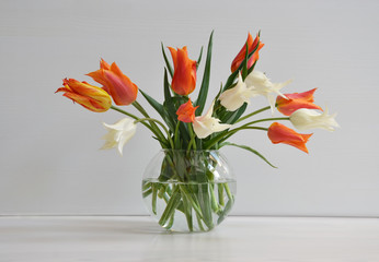 Bouquet of white and orange tulips and lilac in  vase  on white background