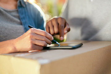 Package Delivery. Close Up Hand Signing On Phone On Box