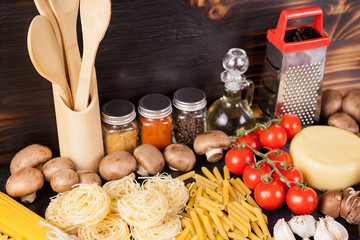 Uncooked raw macaroni, pasta and spaghetti next to fresh and healthy vegetables, variety of spices...
