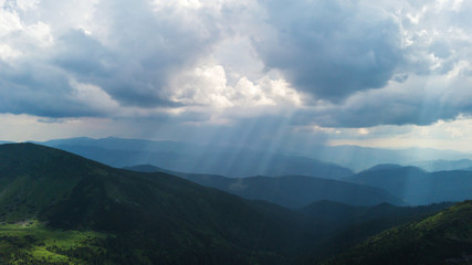 The rays of the sun make their way through the stormy sky in the mountains