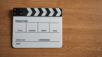 Clapper board or movie slate use in video production or movie and cinema industry. It's white color on wood background.