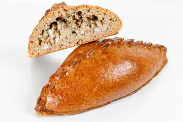 Tasty pastry of rye dough cut in half . Delicious pastries with minced meat on light background.